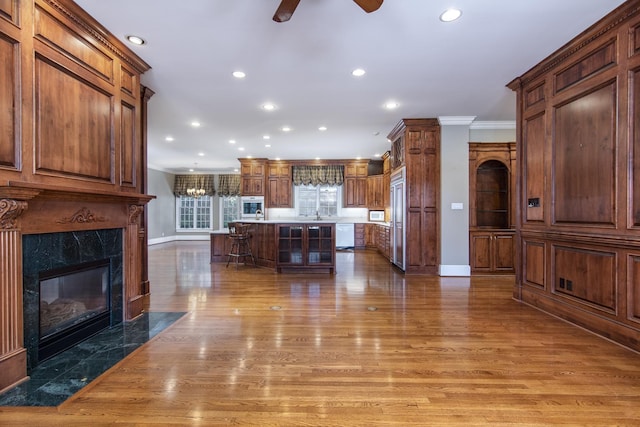 kitchen with a center island, a breakfast bar area, ornamental molding, a high end fireplace, and paneled built in fridge