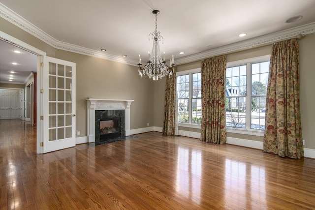 unfurnished living room with a premium fireplace, ornamental molding, a chandelier, and wood-type flooring