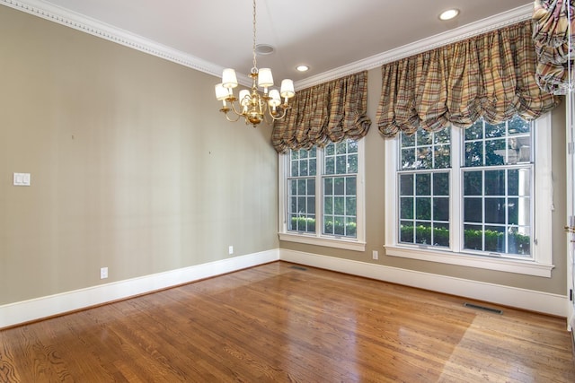 unfurnished dining area featuring a notable chandelier, crown molding, and hardwood / wood-style flooring