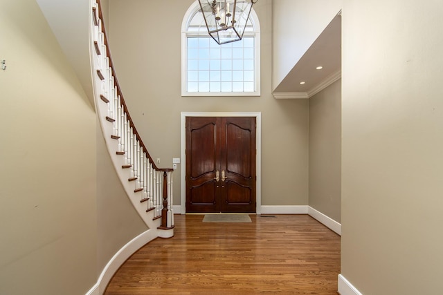 entryway with a chandelier, crown molding, and hardwood / wood-style flooring