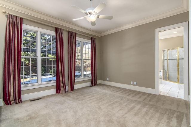 carpeted empty room featuring ceiling fan, crown molding, and plenty of natural light