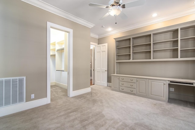 unfurnished office featuring ceiling fan, crown molding, light carpet, and built in desk