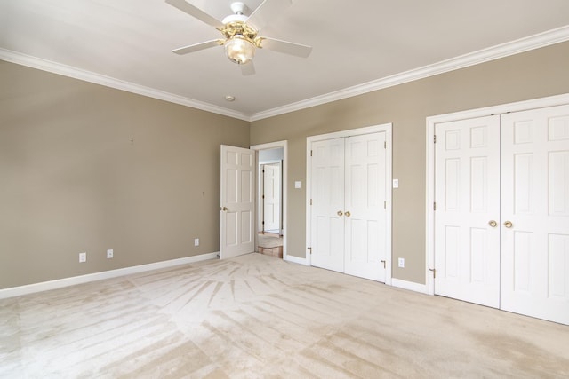 unfurnished bedroom with ceiling fan, light colored carpet, and two closets