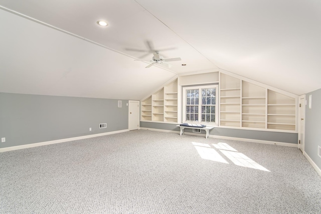 additional living space with ceiling fan, built in shelves, lofted ceiling, and carpet flooring