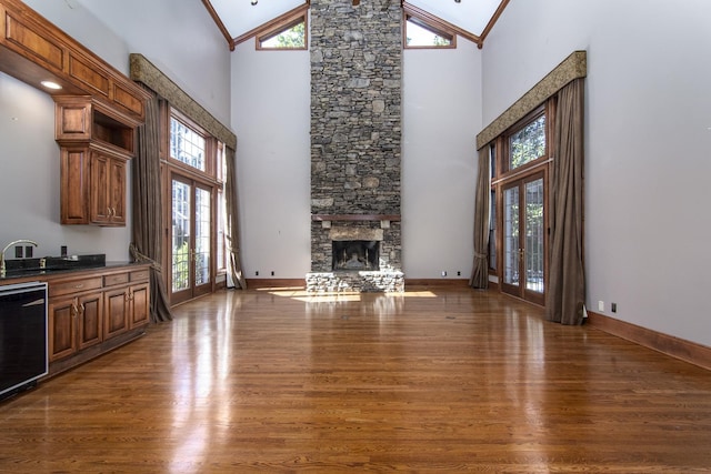 living room featuring high vaulted ceiling, dark wood-type flooring, crown molding, and a stone fireplace