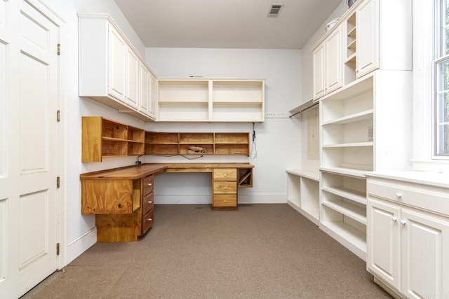 unfurnished office featuring built in desk and dark colored carpet