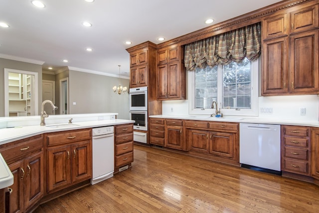 kitchen with stainless steel double oven, dark wood-type flooring, white dishwasher, pendant lighting, and sink