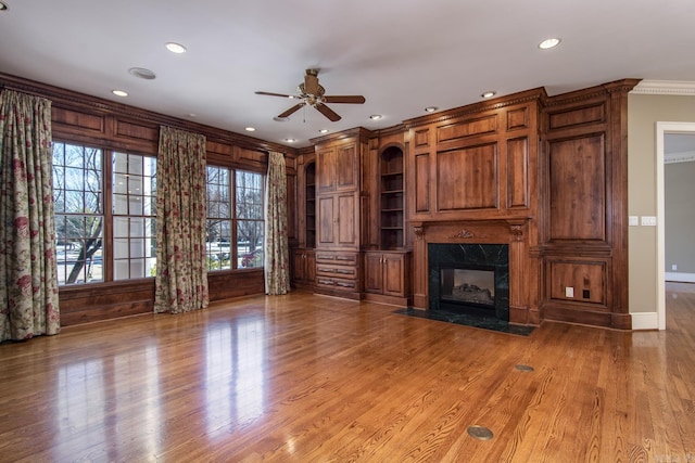 unfurnished living room featuring hardwood / wood-style flooring, crown molding, ceiling fan, and a fireplace