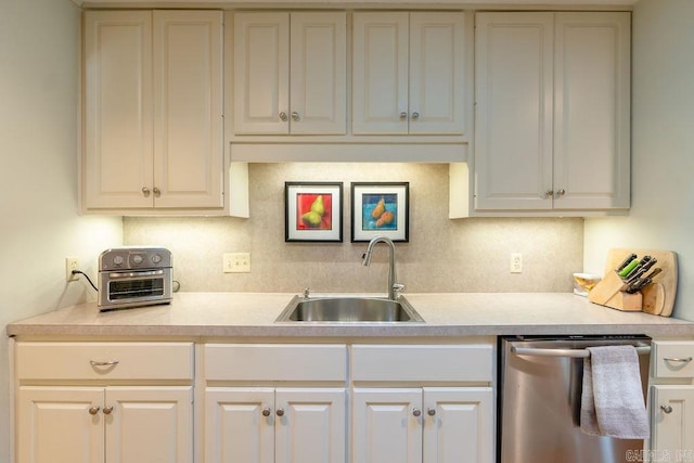 kitchen with tasteful backsplash, white cabinets, dishwasher, and sink