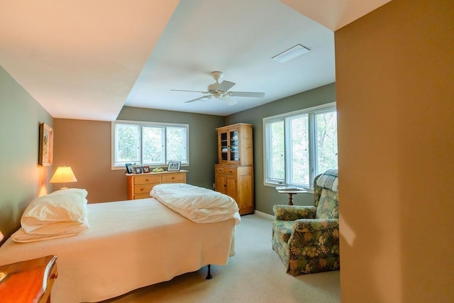 bedroom with ceiling fan, light carpet, and multiple windows