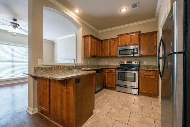 kitchen featuring stone counters, stainless steel appliances, kitchen peninsula, and sink