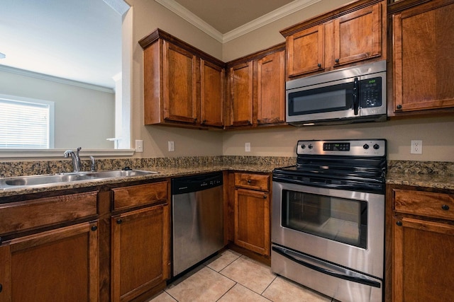 kitchen featuring dark stone countertops, sink, light tile patterned flooring, appliances with stainless steel finishes, and ornamental molding