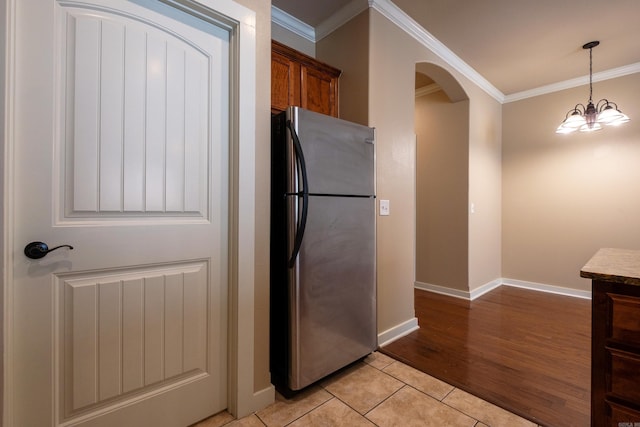 kitchen with crown molding, light tile patterned floors, pendant lighting, and stainless steel refrigerator