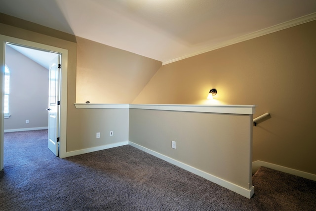 spare room with lofted ceiling, ornamental molding, and dark colored carpet