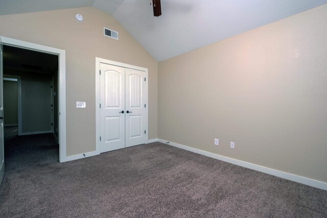 unfurnished bedroom with ceiling fan, a closet, vaulted ceiling, and dark colored carpet