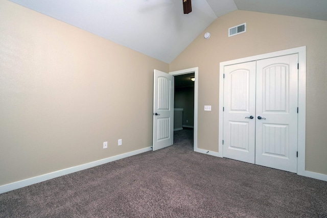 unfurnished bedroom with ceiling fan, dark carpet, a closet, and lofted ceiling