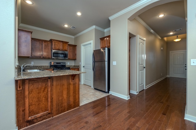 kitchen with stainless steel appliances, crown molding, kitchen peninsula, and sink