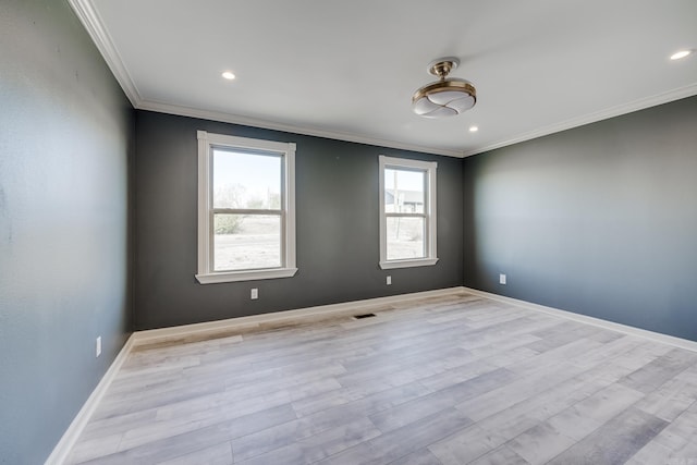 spare room with a wealth of natural light, crown molding, and light hardwood / wood-style flooring