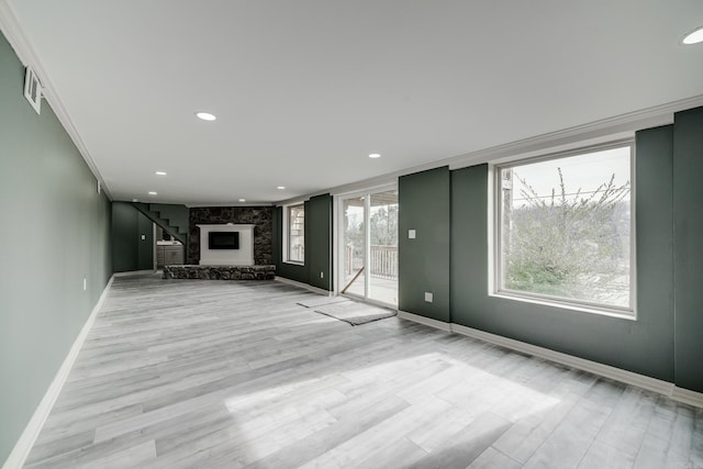 unfurnished living room featuring light hardwood / wood-style flooring, ornamental molding, and a fireplace