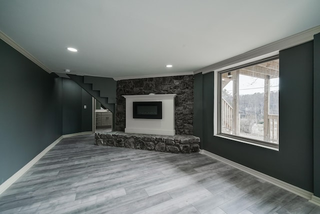 unfurnished living room featuring hardwood / wood-style flooring, crown molding, and a fireplace