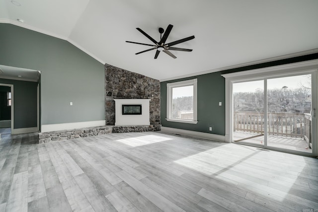 unfurnished living room with vaulted ceiling, a fireplace, crown molding, and light hardwood / wood-style floors