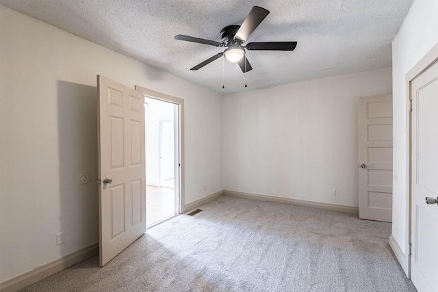 unfurnished bedroom with ceiling fan, light colored carpet, and a textured ceiling