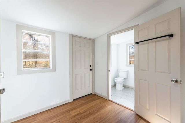 interior space featuring lofted ceiling, a barn door, and light hardwood / wood-style flooring