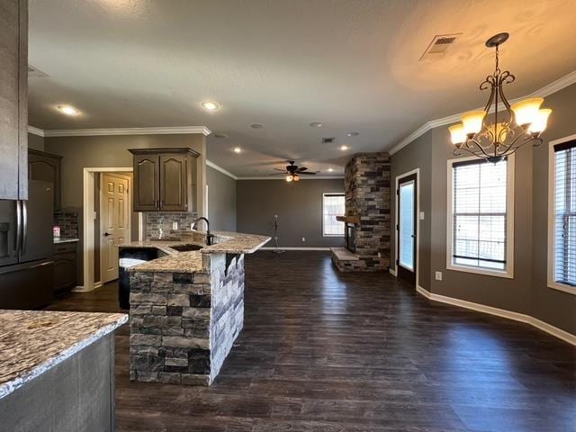 kitchen featuring stainless steel fridge with ice dispenser, pendant lighting, light stone counters, and sink