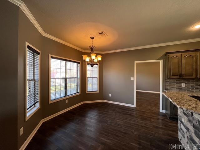 unfurnished dining area with crown molding, dark hardwood / wood-style floors, and a notable chandelier