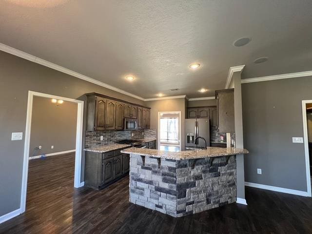 kitchen with appliances with stainless steel finishes, backsplash, dark hardwood / wood-style flooring, ornamental molding, and dark brown cabinetry