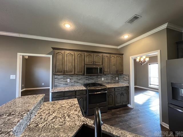 kitchen with appliances with stainless steel finishes, decorative backsplash, light stone countertops, ornamental molding, and dark brown cabinetry