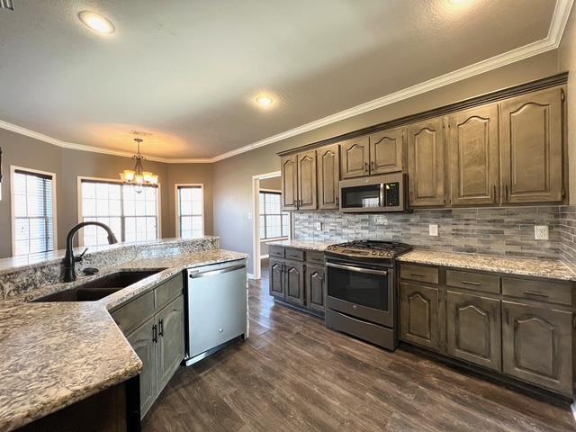 kitchen featuring backsplash, dark hardwood / wood-style floors, sink, hanging light fixtures, and appliances with stainless steel finishes