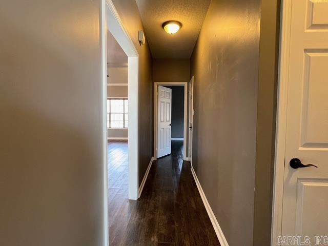 hall with a textured ceiling and dark wood-type flooring