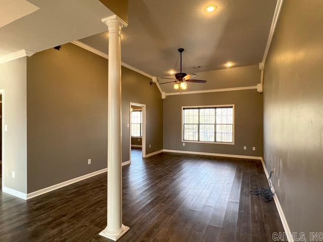 unfurnished living room with dark wood-type flooring, ornate columns, ornamental molding, and ceiling fan