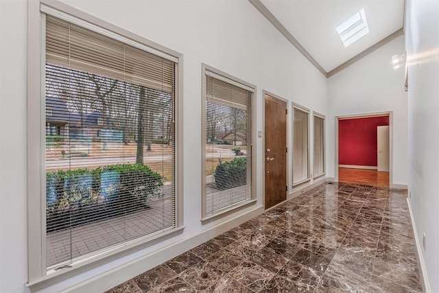 doorway to outside with high vaulted ceiling and a skylight