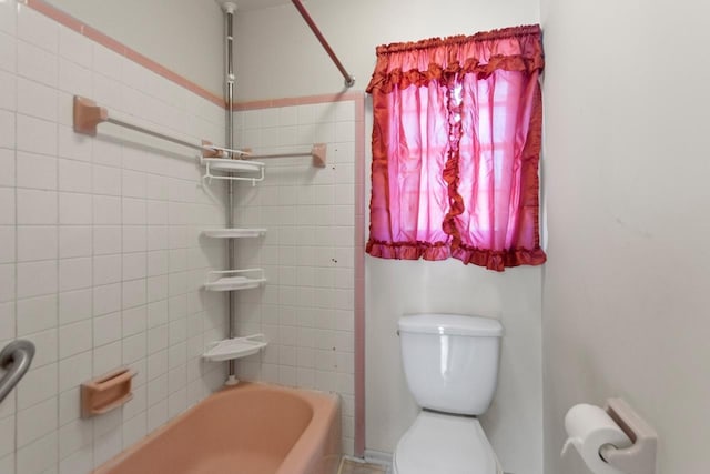 bathroom with toilet and tiled shower / bath combo