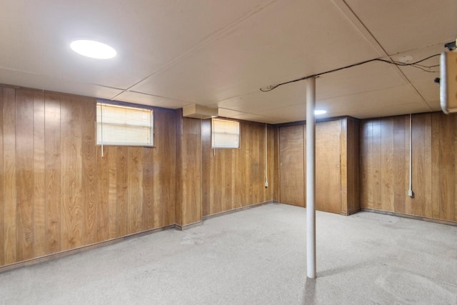 basement featuring light carpet and wood walls