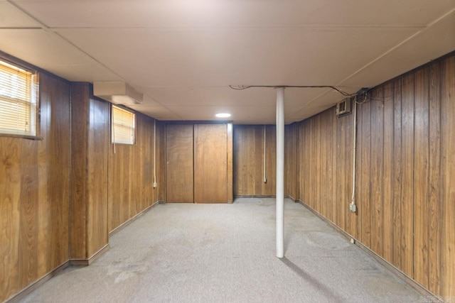 basement featuring light carpet and wooden walls