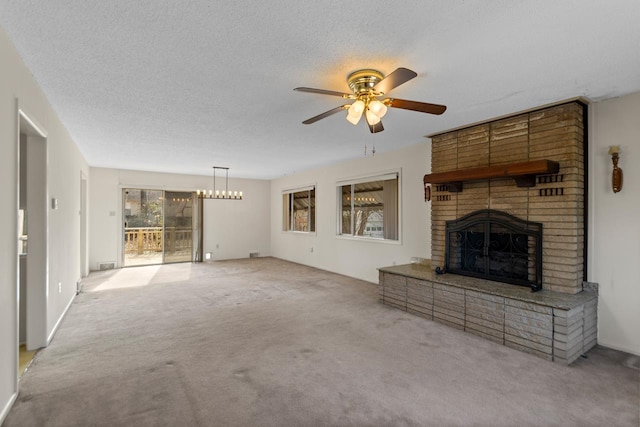 unfurnished living room with ceiling fan with notable chandelier, light colored carpet, a textured ceiling, and a fireplace