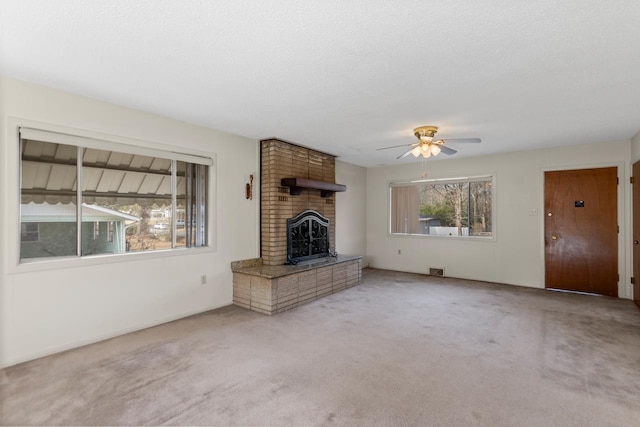 unfurnished living room with light carpet, ceiling fan, a textured ceiling, and a fireplace