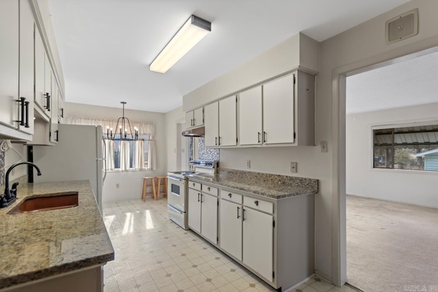 kitchen with decorative light fixtures, sink, white electric range oven, light carpet, and white cabinets