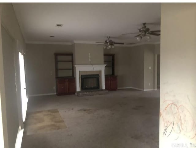 unfurnished living room featuring ceiling fan, ornamental molding, and carpet flooring