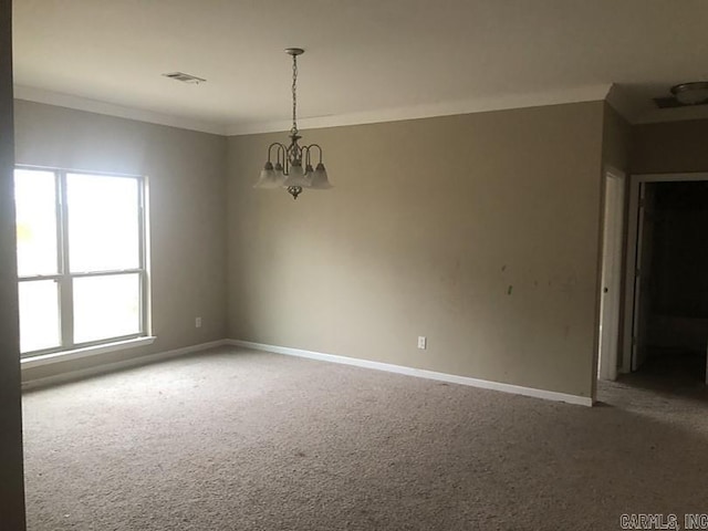 spare room featuring crown molding, carpet floors, and a notable chandelier