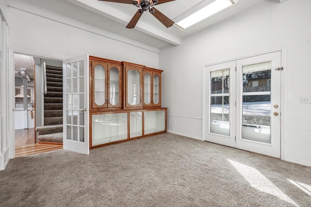 carpeted empty room featuring ceiling fan, beam ceiling, and french doors