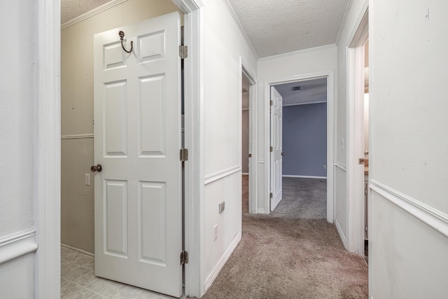 corridor with light carpet, crown molding, and a textured ceiling