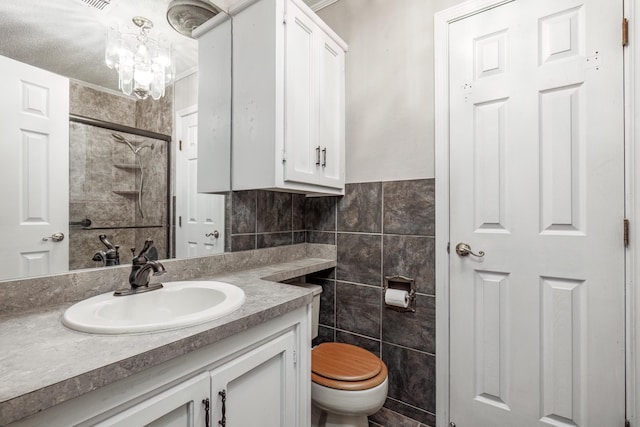 bathroom featuring toilet, vanity, tile walls, a notable chandelier, and a shower with door