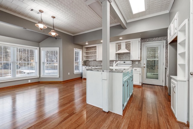 kitchen featuring a kitchen island with sink, decorative light fixtures, ornamental molding, wall chimney exhaust hood, and white cabinets