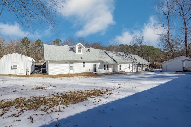 snow covered back of property featuring a storage shed