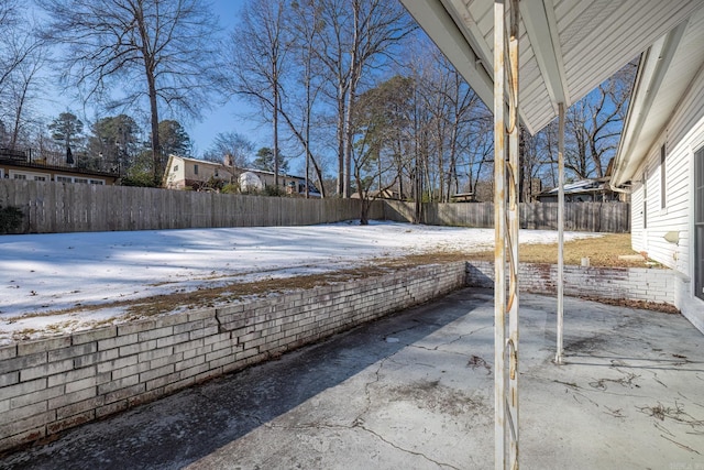 yard layered in snow with a patio area