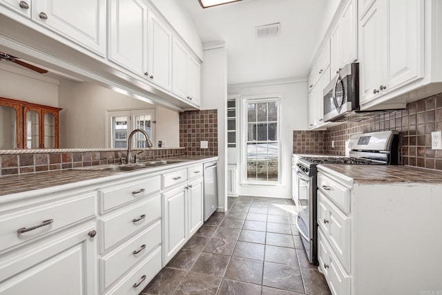 kitchen featuring appliances with stainless steel finishes, white cabinetry, tasteful backsplash, sink, and ceiling fan